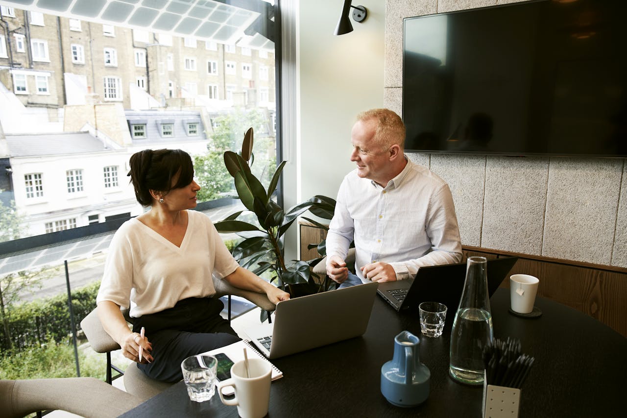 services-04 Two business professionals engaging in a team meeting in a modern London office with a large window view.