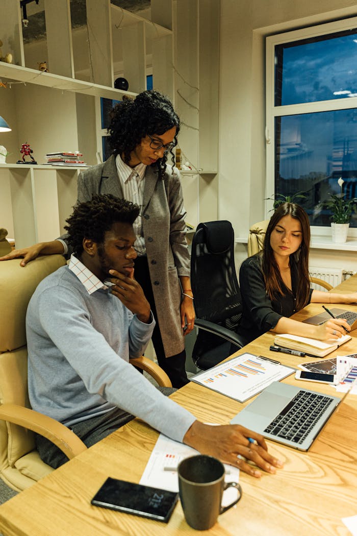 Business team working together at a desk with laptops and documents. Perfect for business collaboration themes.
